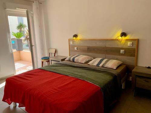 une chambre avec un grand lit avec une couverture rouge dans l'établissement Splendide T3 avec Terrasse et Box Privé à 2 Pas de l'Étang de Thau - FR-1-604-41, à Mèze