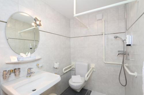 a bathroom with a sink toilet and a mirror at Lifestyle & Spa Hotel Grächerhof in Grächen