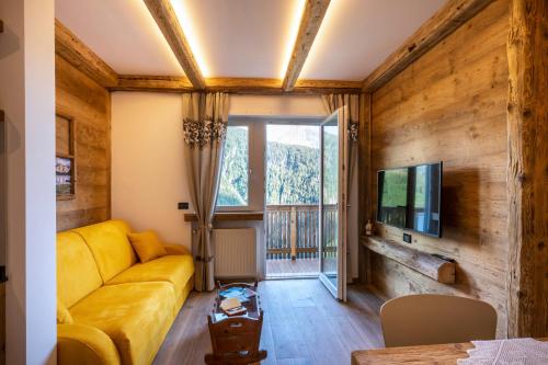 ein Wohnzimmer mit einem gelben Sofa und einem TV in der Unterkunft Cesa dele Angele in Colle Santa Lucia