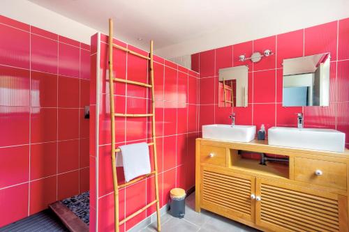 La salle de bains rouge est pourvue d'un lavabo et d'un miroir. dans l'établissement Loft Arvor - Charmant loft avec jardin, à Dinan