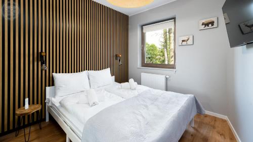 a bedroom with a white bed with a black and white striped wall at Apartamenty Good Time - Stone Hill IV in Szklarska Poręba