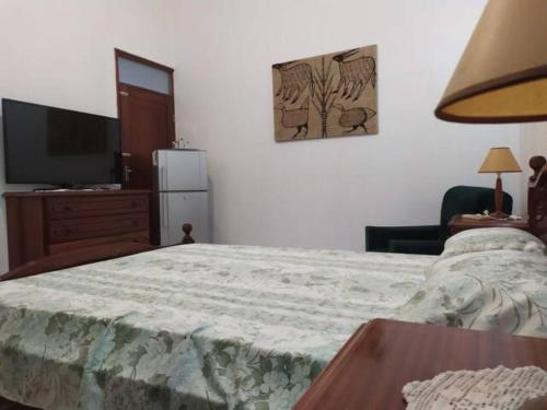 a bedroom with a bed with a table and a television at Cozy Room in Plateau in Praia