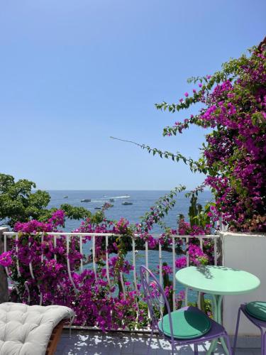 un patio con flores púrpuras, mesa y sillas en La Dolce Vita a Positano boutique hotel, en Positano