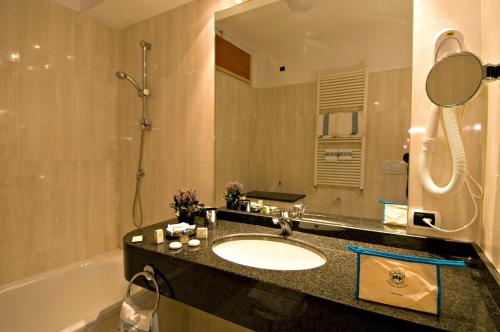 ein Badezimmer mit einem Waschbecken, einer Badewanne und einem Spiegel in der Unterkunft Panoramic Apartments Plaza in Abano Terme