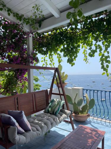 un banco en un patio con vistas al océano en La Dolce Vita a Positano boutique hotel, en Positano