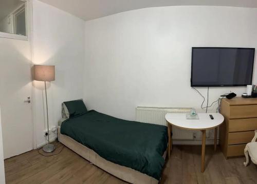 een slaapkamer met een bed en een tafel en een televisie bij Small Studio apartment - quick access to all of london in Londen