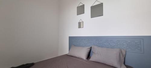 łóżko w białym pokoju z 3 zdjęciami na ścianie w obiekcie Maison dolce vita w mieście Ţūzah