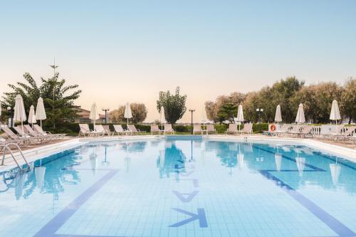 a large swimming pool with chairs and umbrellas at Kalamaki Beach Hotel, Zakynthos Island in Kalamaki