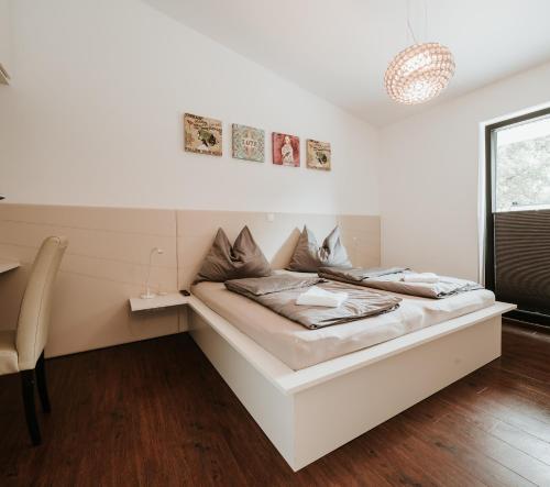 a white bedroom with a bed and a chair at Haus Sommerfrische in Weyregg