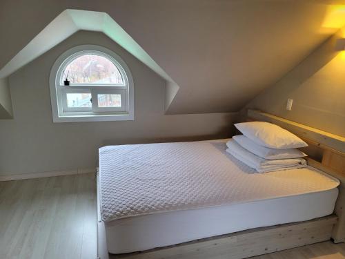 a bedroom with a bed with an attic window at Leve de Mongdol Pension in Geoje