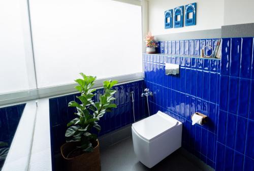 a blue tiled bathroom with a toilet and a plant at ELIVAAS 5 BHK with Pvt Pool, Entertainment Room & Glass House - Bludoor in Marmagao