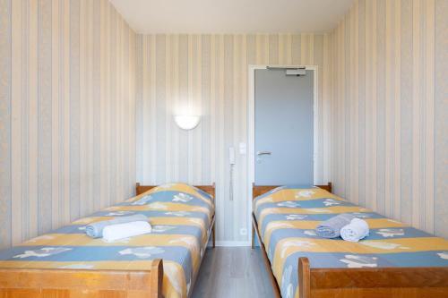 two beds in a room with striped walls at Logis Hôtel La crémaillère in Hagetmau