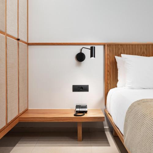 a bedroom with a bed and a table with a clock on it at Caravia Beach Hotel in Marmari