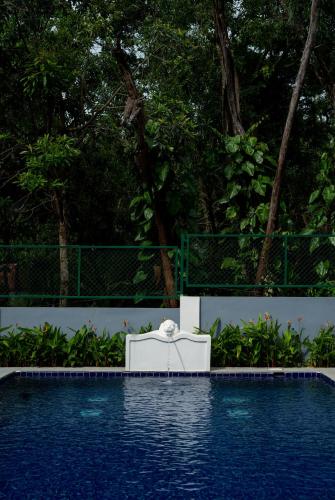 a white chair sitting next to a swimming pool at ELIVAAS 5 BHK with Pvt Pool, Entertainment Room & Glass House - Bludoor in Marmagao