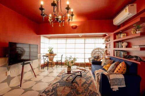 een woonkamer met rode muren en een blauwe bank bij Elivaas Bludoor Luxe 5BHK Villa with Pvt Pool, Assagao in Marmagao