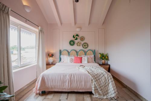 a bedroom with a bed with pink pillows and a window at ELIVAAS 5 BHK with Pvt Pool, Entertainment Room & Glass House - Bludoor in Marmagao