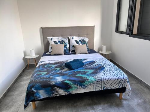 a bedroom with a bed with a blue and white comforter at Arbre à pain in Bras-Panon