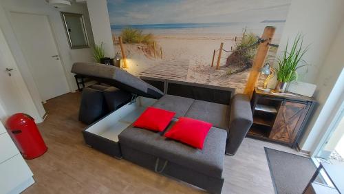 a living room with a gray couch with two red pillows at Ferienwohnung Ostsee Graal-Müritz Küstenwald in Gelbensande