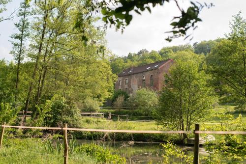 un vieux bâtiment en brique à côté d'une masse d'eau dans l'établissement Mégi des Aguesses, à Andenne