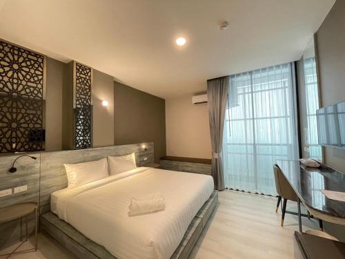 a bedroom with a bed and a desk and a window at วัน บัดเจท เชียงราย เชียงแสน One Budget Hotel Chiangrai Chiangsaen in Ban Lan Dok Mai