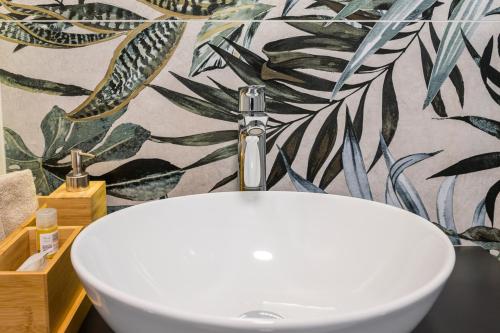 a white sink in a bathroom with a tropical wallpaper at Hermes Sea View in Stalos