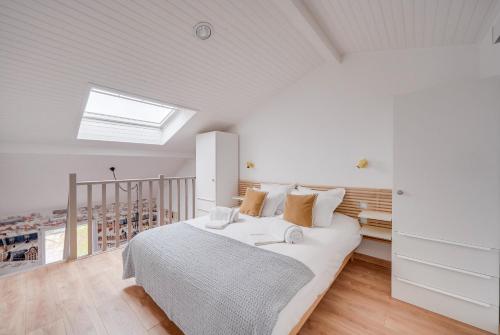 - une chambre blanche avec un lit et une lucarne dans l'établissement Les Toits - Location Moyenne Durée - Centre, à Bordeaux