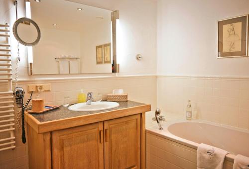 a bathroom with a sink and a tub and a mirror at BLEICHE RESORT & SPA in Burg