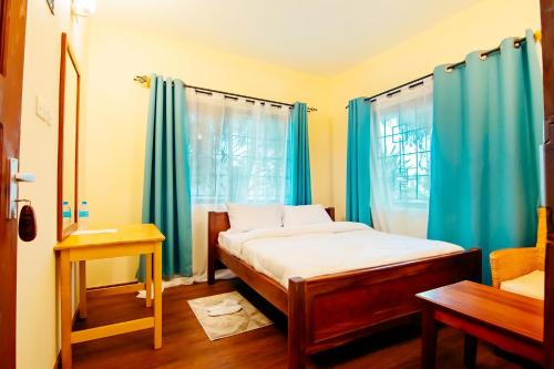 ein kleines Schlafzimmer mit blauen Vorhängen und einem Bett in der Unterkunft Bamboo Village in Arusha