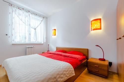 a bedroom with a bed with red pillows and a window at Morena in Ełk