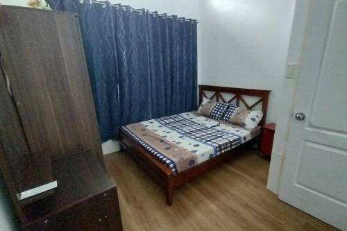 a small bedroom with a bed with blue curtains at 2 Storey House 4 BR Diamond Heights Near Airport in Davao City