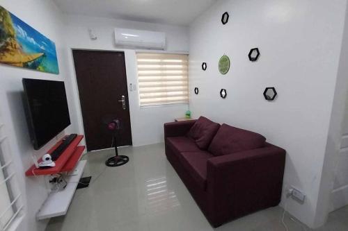a living room with a couch and a tv at 2 Storey House 4 BR Diamond Heights Near Airport in Davao City