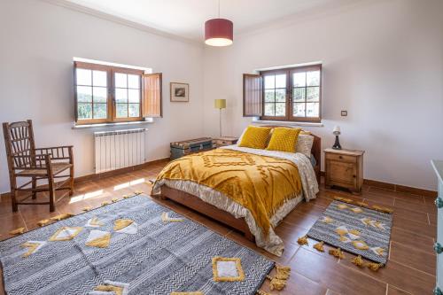a bedroom with a bed and a chair and windows at Quinta da Palhota in Vila de Rei