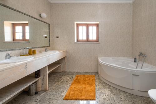 a bathroom with two sinks and a tub and a mirror at Quinta da Palhota in Vila de Rei