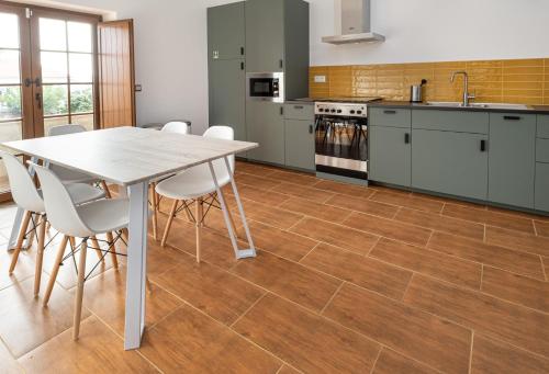 a kitchen with a table and white chairs at Quinta da Palhota in Vila de Rei