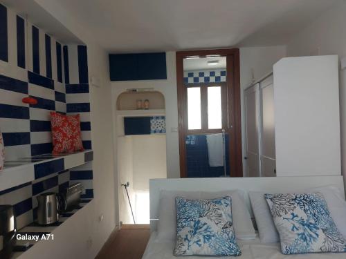 a bedroom with a white bed with blue and white pillows at Coralinetiny in Castellammare di Stabia