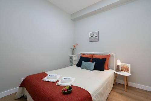 a white bedroom with a bed with a red blanket at Host Wise - Modern Flats with Stunning Terrace or Balcony - Central Location in Porto
