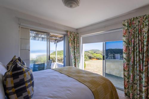 a bedroom with a bed and a large window at Dunes Cottage in Plettenberg Bay