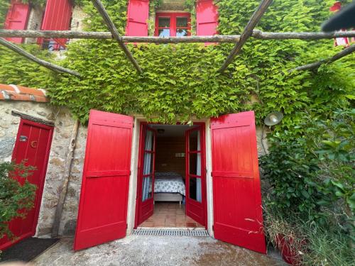 a red door entrance to a building with ivy at Mas Lo Faix in Saint-Laurent-de-Cerdans