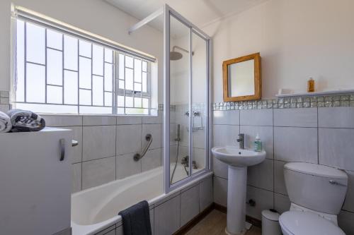 a bathroom with a shower and a toilet and a sink at Dunes Cottage in Plettenberg Bay