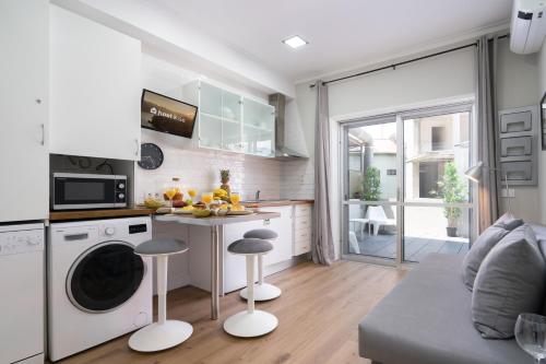 a kitchen with a washing machine and two stools at Host Wise - Modern Flats with Stunning Terrace or Balcony - Central Location in Porto