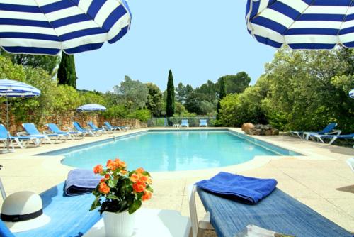 einen Pool mit Stühlen und einer Vase aus Blumen in der Unterkunft Le Mas des Collines in Tourtour