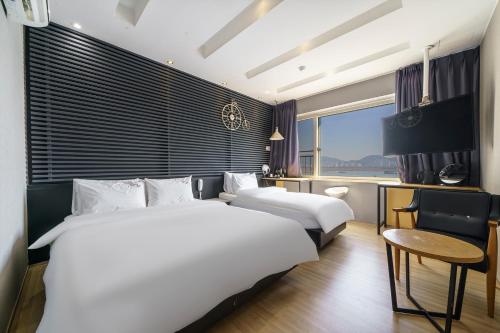 a hotel room with two beds and a desk at JK Hotel in Busan