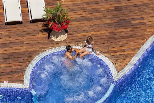 Dos chicas están sentadas en una piscina en Ona Palmira Paradise en Paguera