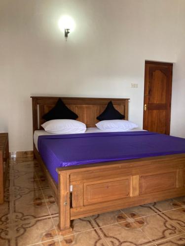 uma cama com lençóis e almofadas roxos num quarto em Springvalley Holiday Home em Badulla