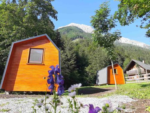 a small house in a field with mountains in the background at Camping & Glamping Grintovec in Preddvor