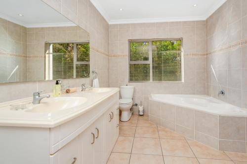 La salle de bains est pourvue de 2 lavabos, d'une baignoire et de toilettes. dans l'établissement Coney Glen Penthouse, à Knysna