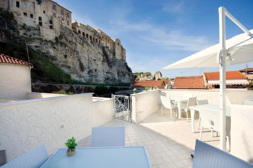 een patio met tafels en stoelen en een parasol bij Residenza a due passi dal mare in Tropea