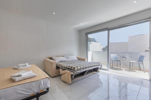 a white room with a bed and a large window at Studio Penthouse 51 with side sea views at the OLO Living guesthouse in Paceville