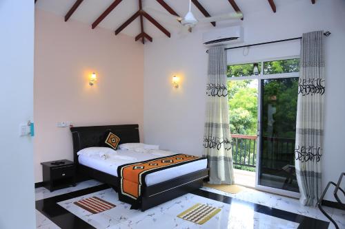 a bedroom with a bed and a large window at Hotel River Front in Tissamaharama