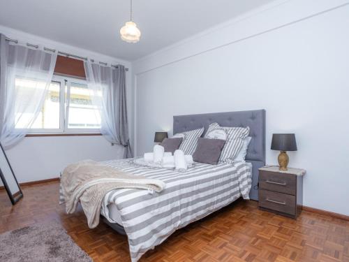 a white bedroom with a bed and a window at Figueira Casino Center Apartment in Figueira da Foz